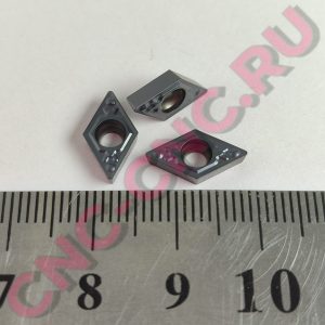 Close-up of a metal ruler with centimeter marks and small gray plastic bricks scattered on it, with a pink COPY watermark present.