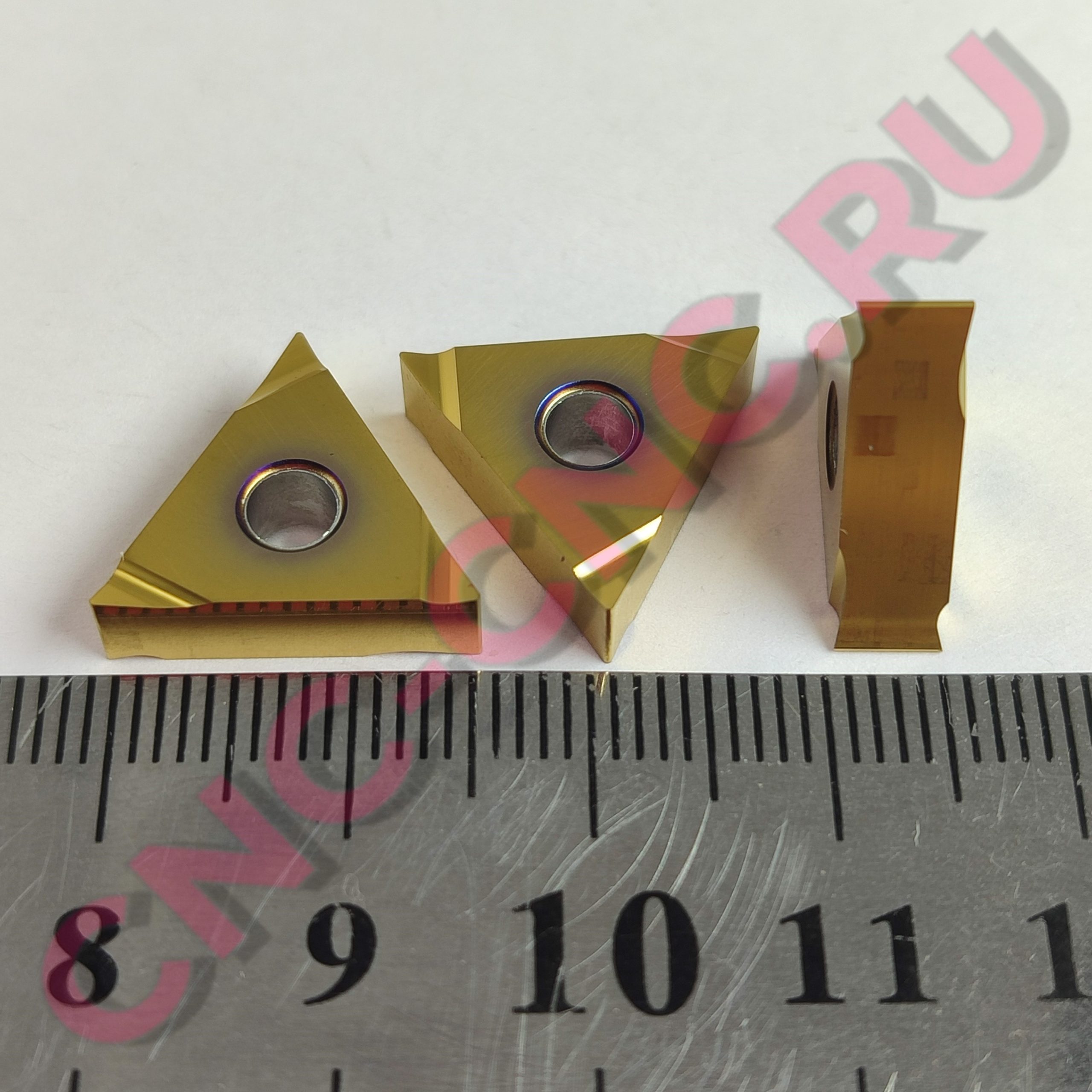 Close-up of gold folded paper shapes arranged on a ruler, with pink numbers overlaid across the image.