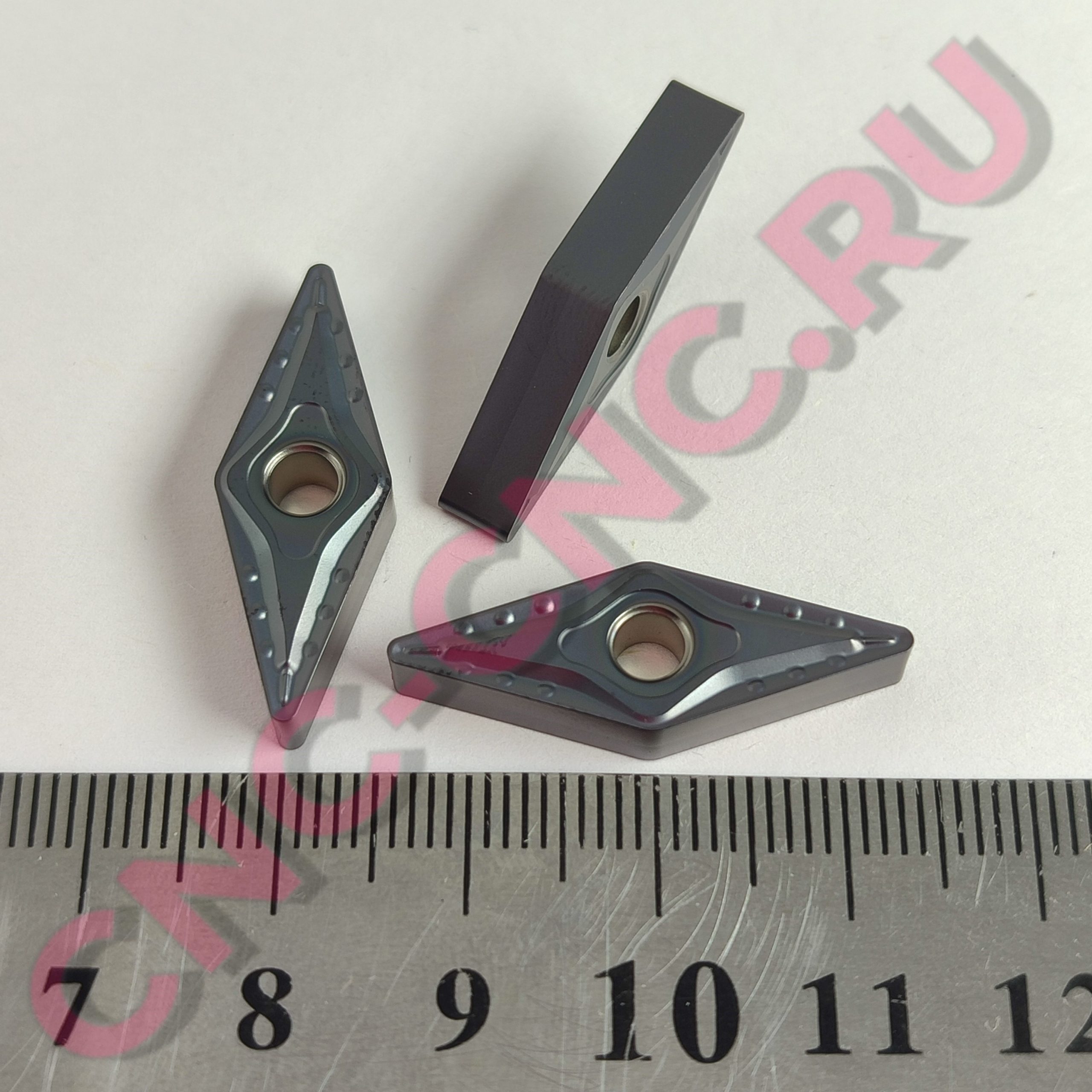 Close-up of two gray metal binder clips on a light surface with a centimeter ruler for scale visible nearby.